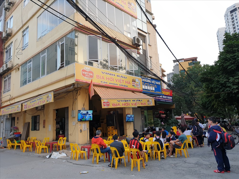 Một quán bia hơi trên phố Trung Kính vắng hoe khách nhậu. Thay vào đó, các em học sinh trong giờ tan học xin chủ quán ngồi nhờ để chờ phụ huynh đến đón và theo dõi trận đấu. Ảnh: Tùng Giang.