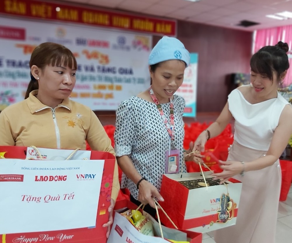 Bà Nguyễn Ngọc Anh Thư, đại diện Công ty VNPAY (bìa phải), tặng quà cho chị Đậu Thị Lê và chị Đoàn Thị Nga, CN Công ty PouYuen, quê ở Nam Định, một mình đi làm nuôi chồng bị bệnh và 3 con nhỏ, đã 15 năm không được về quê đón Tết. Ảnh Nam Dương