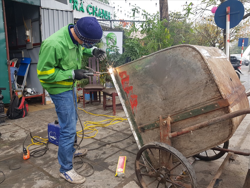Những công nhân vệ sinh chỉnh sửa lại chiếc xe rác sau một năm chiếc xe gắn bó với mình.