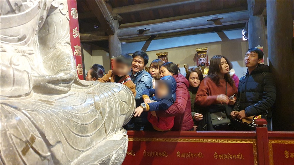 Thậm chí nhiều du khách còn chen chúc, bồng bế cả con nhỏ để dàng chạm vào thân tượng.