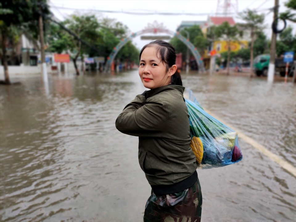 Chị Thu Hiền (22 tuổi, trú tại TP. Hà Tĩnh) tỏ ra vui vẻ khi mua được thực phẩm, mang về nhà (chỗ đang còn ngập sâu) để gia đình sử dụng trong những ngày chờ nước lũ rút hẳn. Ảnh: Quách Du
