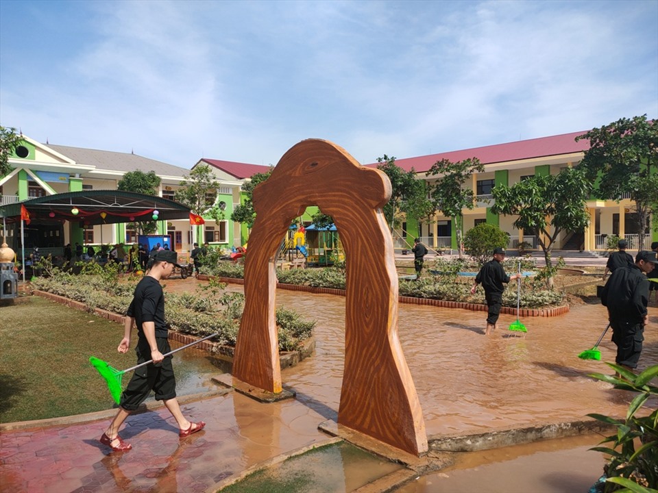 Hàng chục cán bộ Phòng Cảnh sát Cơ động Công an tỉnh Hà Tĩnh được điều động đến giúp trường dọn dẹp sau lũ. Ảnh: Quách Du