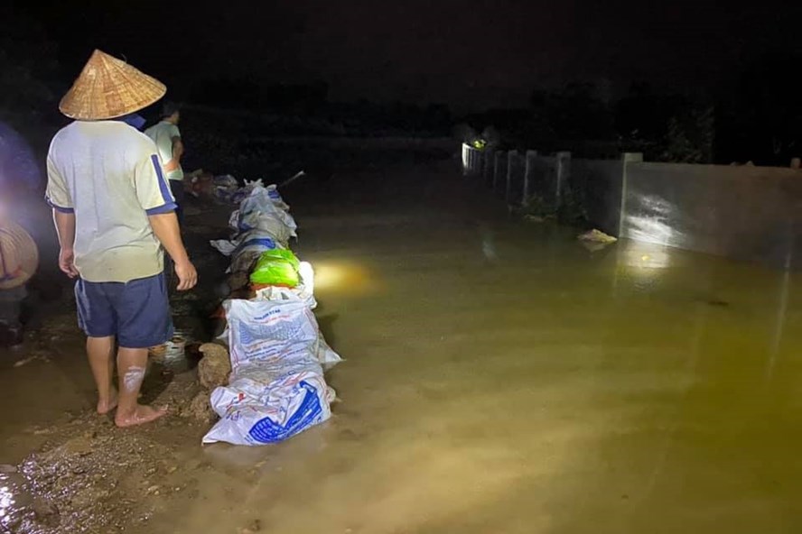 Người dân xã Thượng Lộc dùng bao bì chứa đất đắp đê trong đêm để ngăn lũ đổ về làng. Ảnh: TP.
