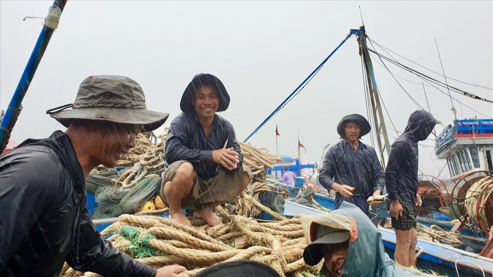 Mặc dù thời tiết mưa bão nhưng tinh thần làm việc trên tàu của các ngư dân đều hối hả và vô cùng vui vẻ. Với mọi người, việc giữ một tinh thần thoải mái, tâm lý sẵn sàng là một điều kiên quyết để vươn khơi bám biển ngay khi bão tan. Ảnh: Hữu Long
