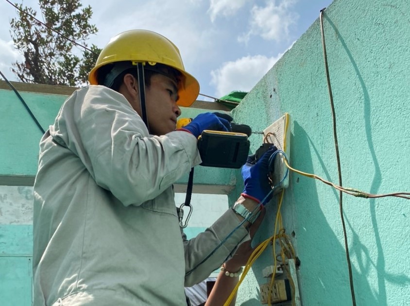 Người lao động của EVNHCMC giúp người dân miền Trung bị lũ lụt sửa chữa lại hệ thống điện gia đình. Ảnh Đức Long