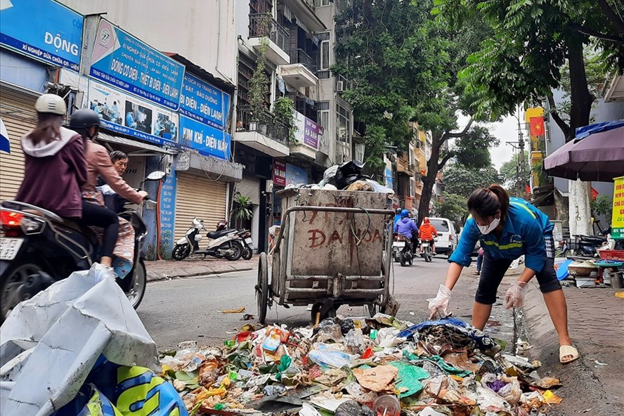 Công nhân môi trường đô thị căng mình thu gom rác trên phố Yên Phụ (quận Tây Hồ, Hà Nội). Ảnh: Anh Thư