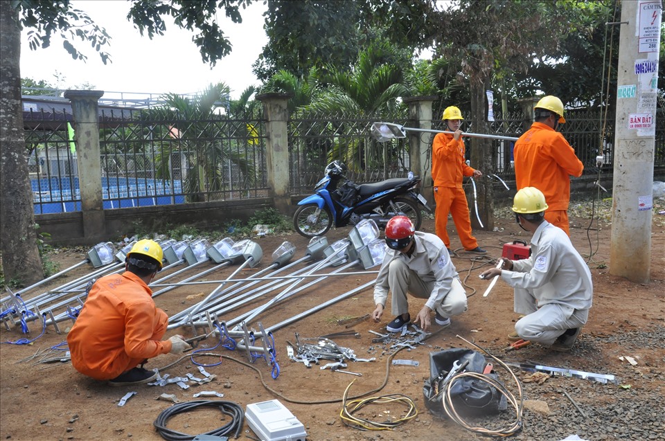 Công nhân ngành điện hỗ trợ lắp đặt điện cho người dân khó khăn. Ảnh: Hương Cẩm