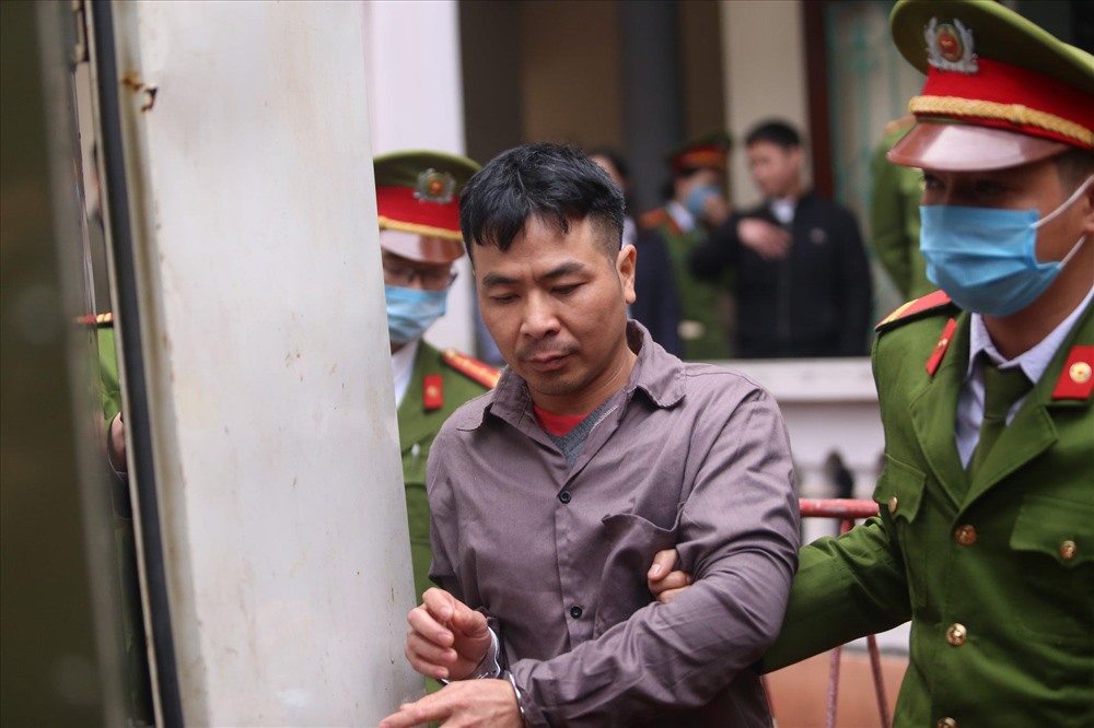Bị cáo Sơn (trái, áo sẫm màu) bị dẫn giải vào phòng xử.