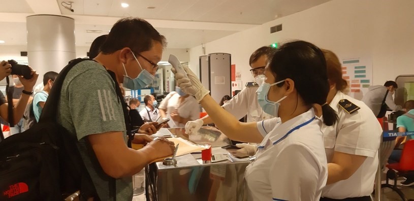 Hành khách làm tờ khai y tế và được kiểm tra thân nhiệt. Ảnh: