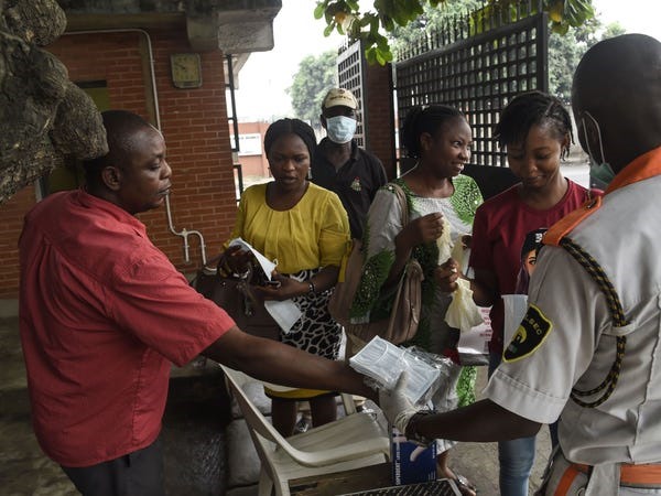 Người dân được phát khẩu trang, găng tay và nước khử trùng tay khi đi qua cổng an ninh ở Lagos, Nigeria. Ảnh: Reuters
