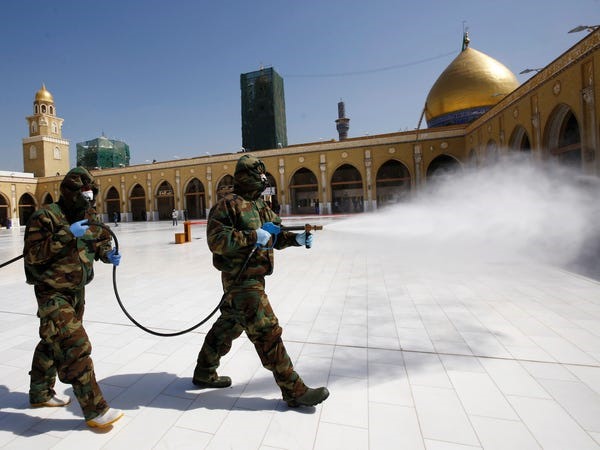 Các thành viên của đội phòng vệ dân sự phun thuốc khử trùng để vệ sinh xung quanh nhà thờ Hồi giáo Kufa, tại thành phố thánh địa Najaf, Iraq. Ảnh: Reuters
