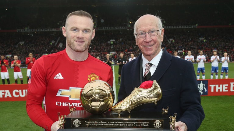 Sir Bobby Charlton trao cho Rooney biểu tượng chiếc giày vàng sau khi Rooney phá kỷ lục ghi bàn cho MU do mình nắm giữ.