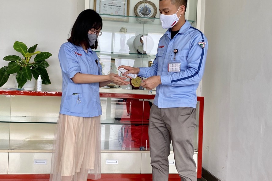 Công nhân viên Công ty Yamaha Motor Viá»t Nam thá»±c hiá»n Äeo khẩu trang, xá»t nưá»c diá»t khuẩn trưá»c khi và o là m viá»c. Ảnh: H.A