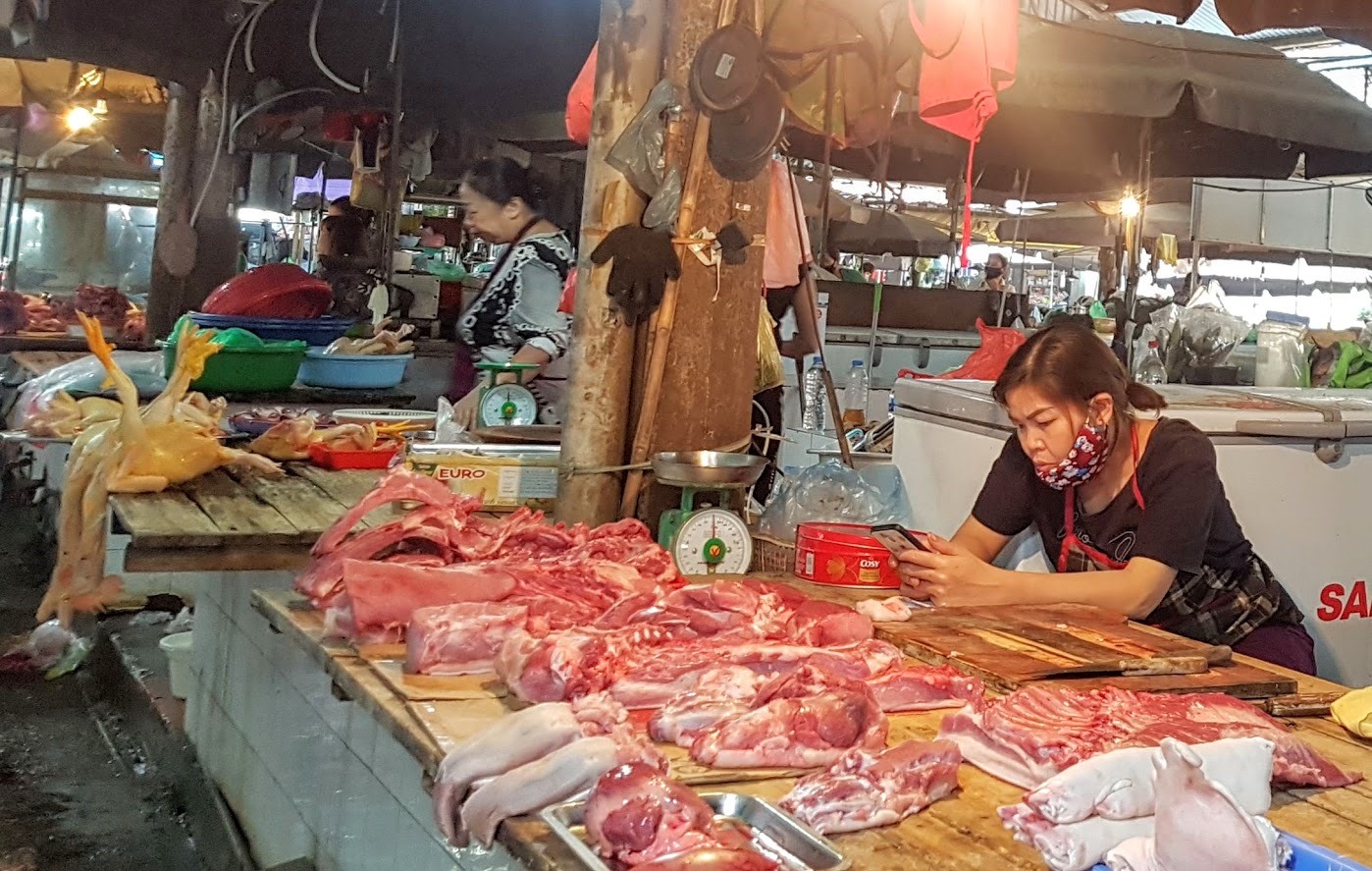 Vắng khách mua hàng, một tiểu thương ngồi nghịch điện thoại. Ảnh: Kh.V
