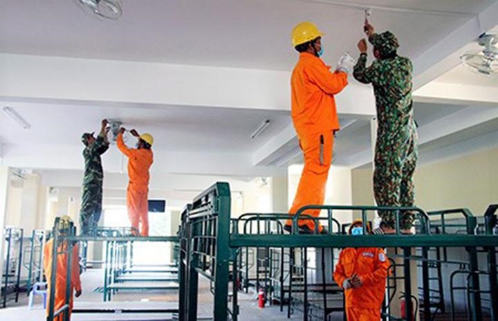 Công nhân Công ty điện lực Hậu Giang phối hợp cùng các chiến sĩ quân đội kiểm tra, lắp đặt các thiết bị điện, đảm bảo cung cấp điện cho địa điểm cách ly phòng, chống dịch COVID-19. Ảnh Đình Hoàng.