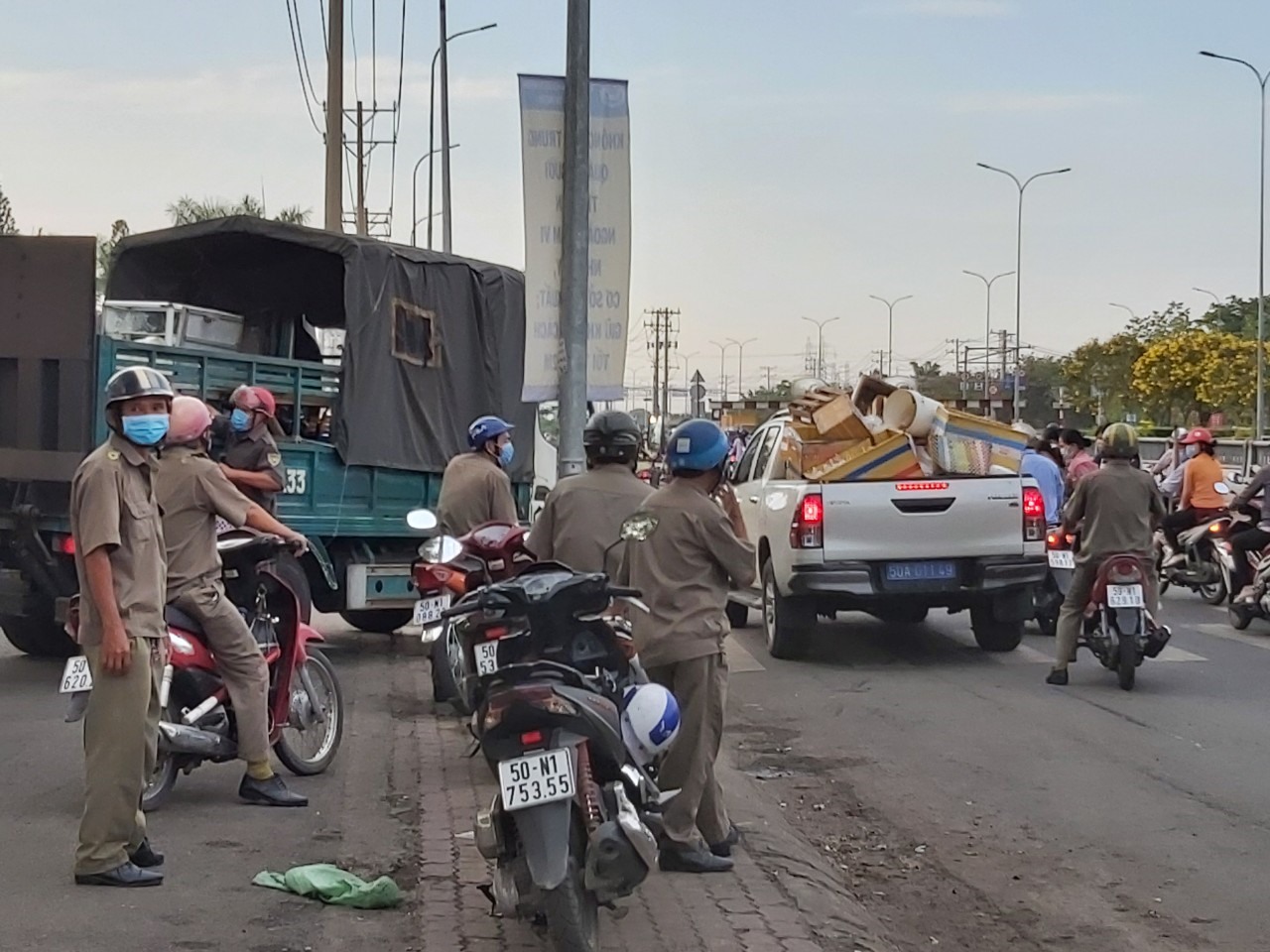Lực lượng chức năng của Quận Bình Tân và Phường Tân Tạo thu gom đồ bán hàng rong trước cổng Công ty PouYuen sáng 16.4. Ảnh Đức Long