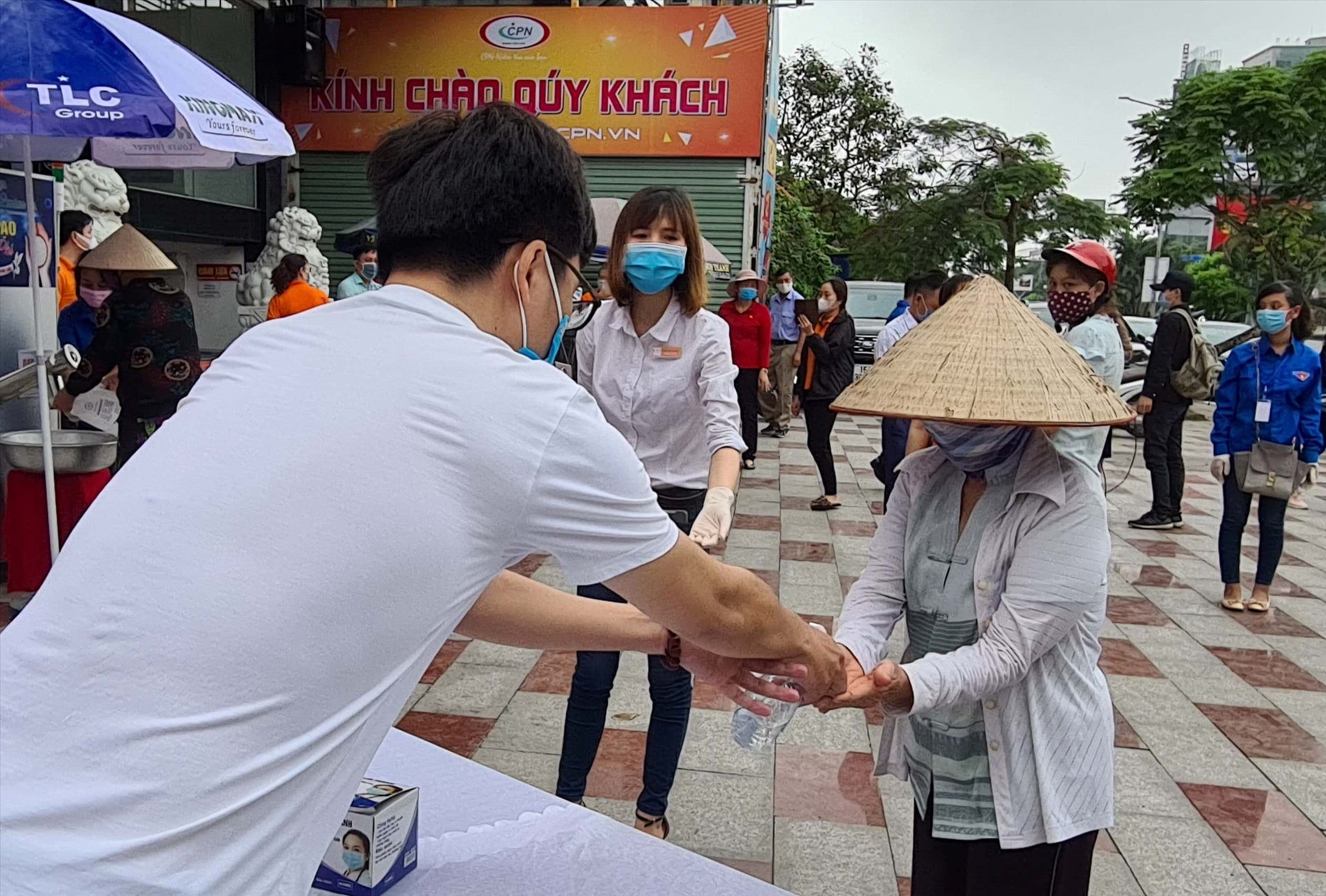 Người dân được sát khuẩn tay trước khi vào nhận gạo tại cây ATM. Ảnh Đặng Luân