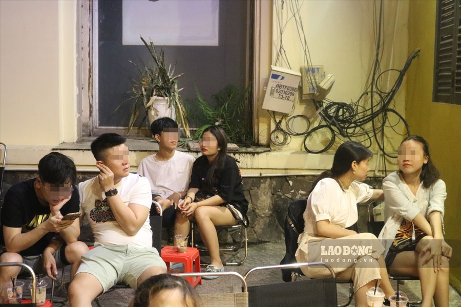 Quán càphê tận dụng vỉa hè sát cửa hàng để cho khách ngồi. Các khách hàng ngồi tại quán, vỉa hè không đeo khẩu trang và không đảm bảo khoảng cách an toàn theo khuyến cáo. Ảnh: Hà Phương.
