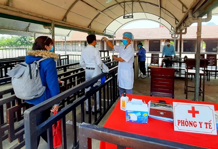 Nhân viên y tế kiểm tra sức khỏe và đo thân nhiện đối với khách tham quan tại chùa Bái Đính. Ảnh: NT