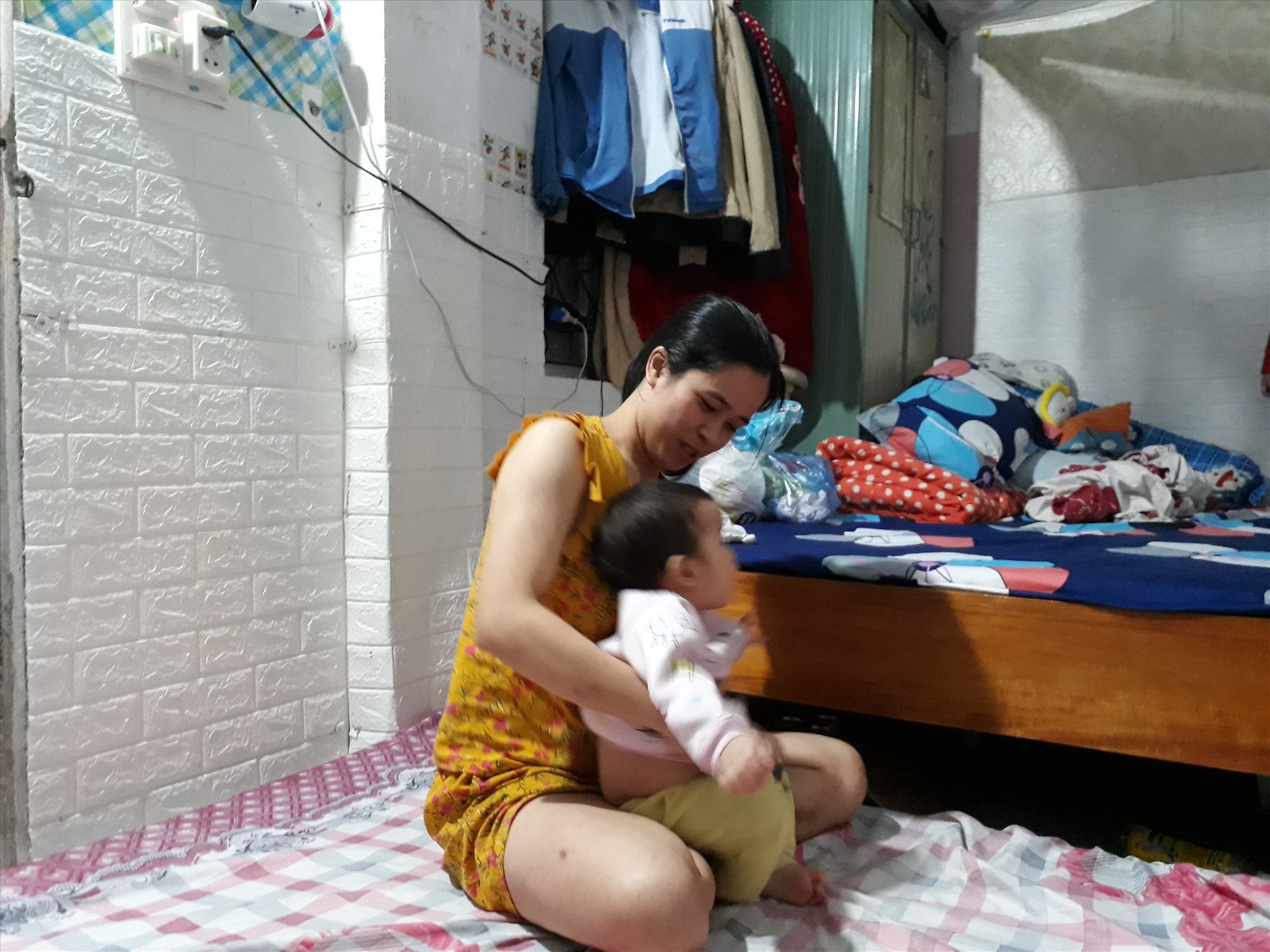 Chị Phan Thị Ngọc Quyên cùng con trong căn phòng trọ tại thôn Nhuế (xã Kim Chung, Đông Anh, Hà Nội). Ảnh: Quế Chi