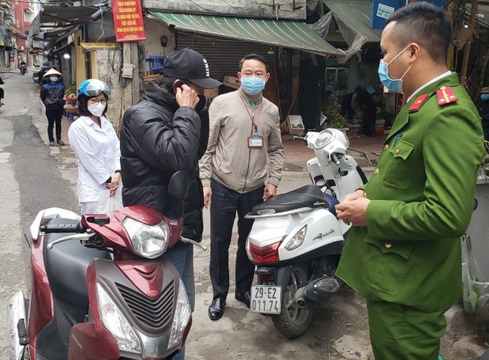 Lực lượng chức năng quận Đống Đa nhắc nhở, xử phạt các trường hợp không đeo khẩu trang ra đường. Ảnh: Linh Nhi