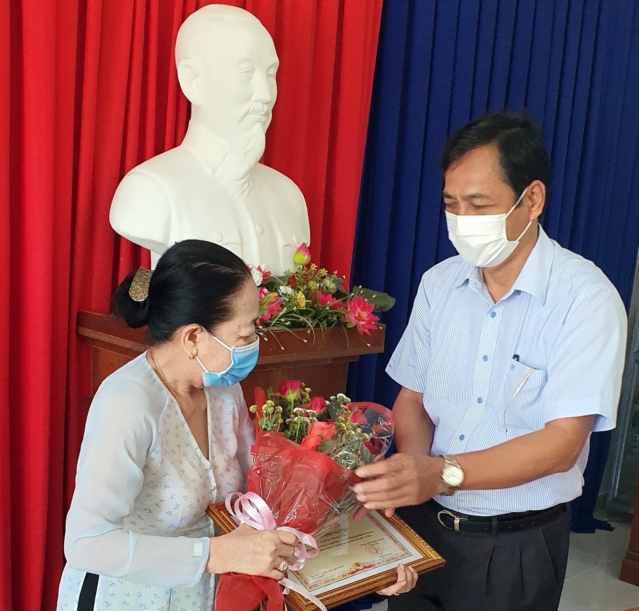 Phó chủ tịch UBND tỉnh Cà Mau Trần Hồng Quân tặng hoa, trao bằng khen cho cụ bà ủng hộ tiền phòng chống dịch COVID-19 (ảnh Nhật Hồ)