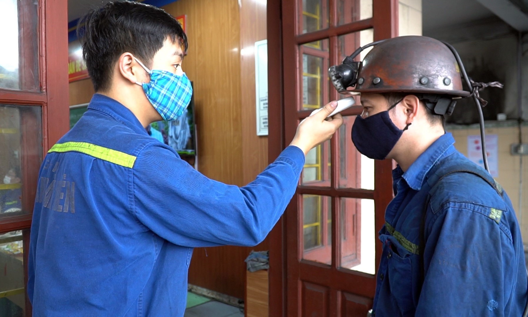 Kiểm tra thân nhiệt nhiều vòng: từ trên xe ô tô đưa đón công nhân đến lúc vào khai trường. Ảnh: Phạm Cường