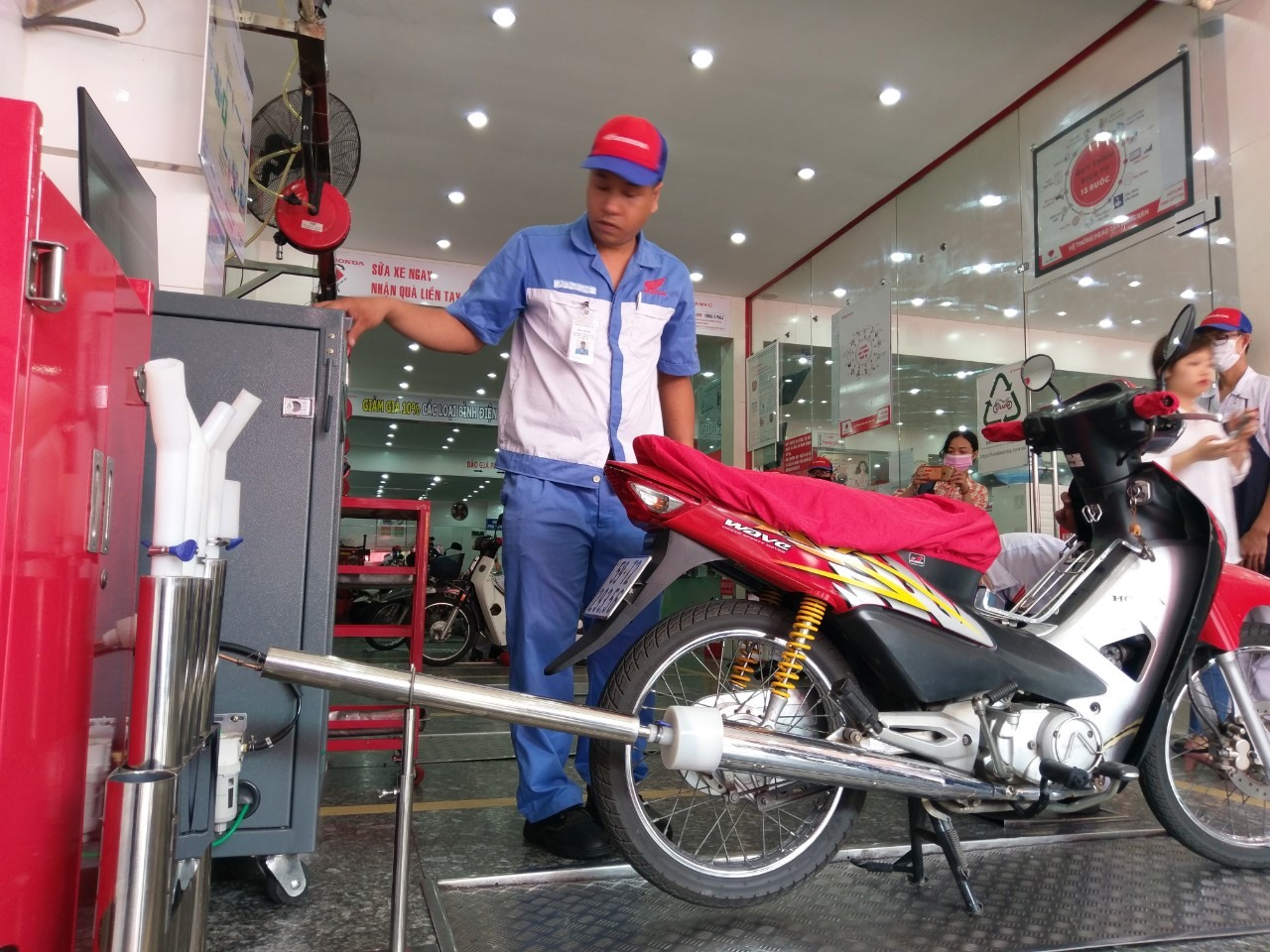 Nhân viên tiến hành kiểm tra khí thải xe máy. Ảnh: Minh Quân