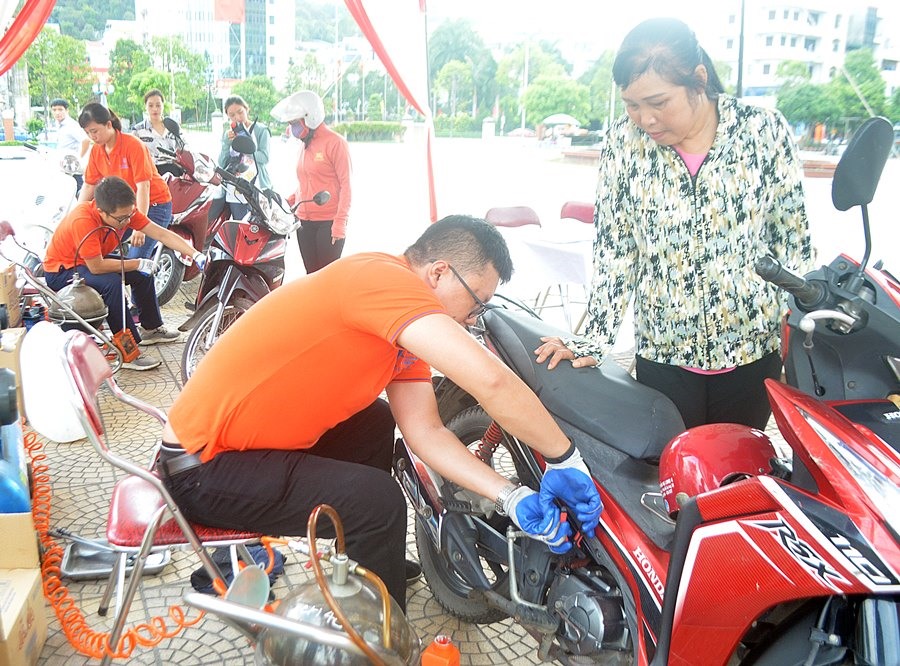 Nhân viên Công ty Xăng dầu B12 thay dầu xe máy miễn phí cho đoàn viên Công đoàn. Ảnh: Dương Trường