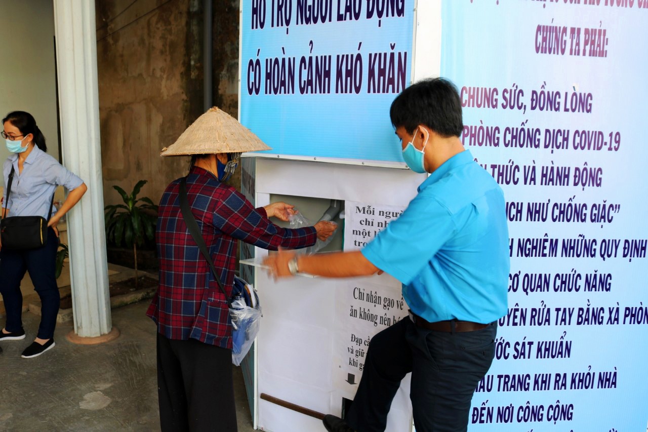 Cán bộ LĐLĐ tận tình hướng dẫn NLĐ thực hiện thao tác nhận gạo. Ảnh: LT