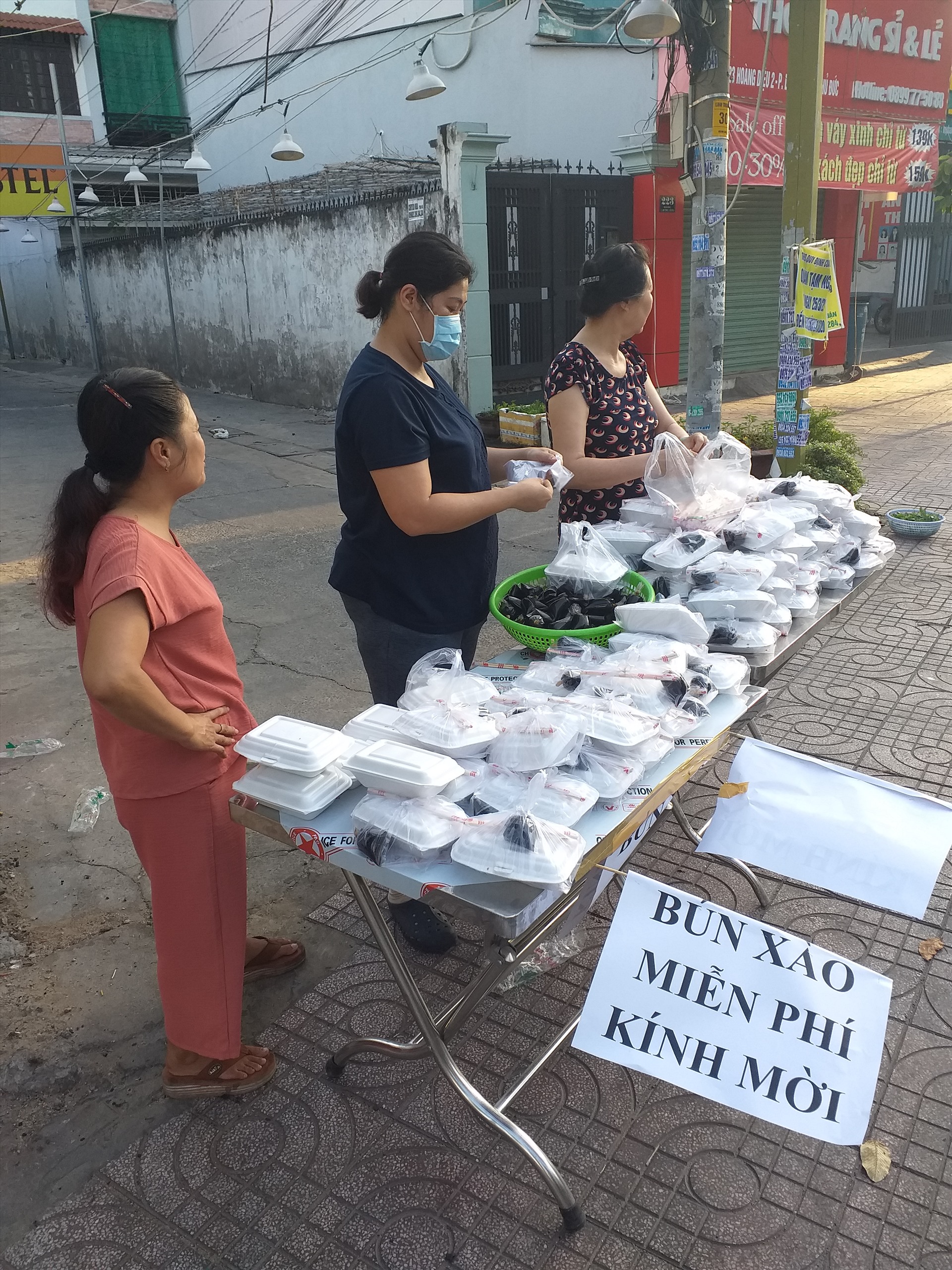 Chị Ngọc (người đứng giữa) đang chuẩn bị phần ăn sáng để phát cho mọi người đến nhận tại số 219 đường Hoàng Diệu 2, phía trước cổng nhà mình.
