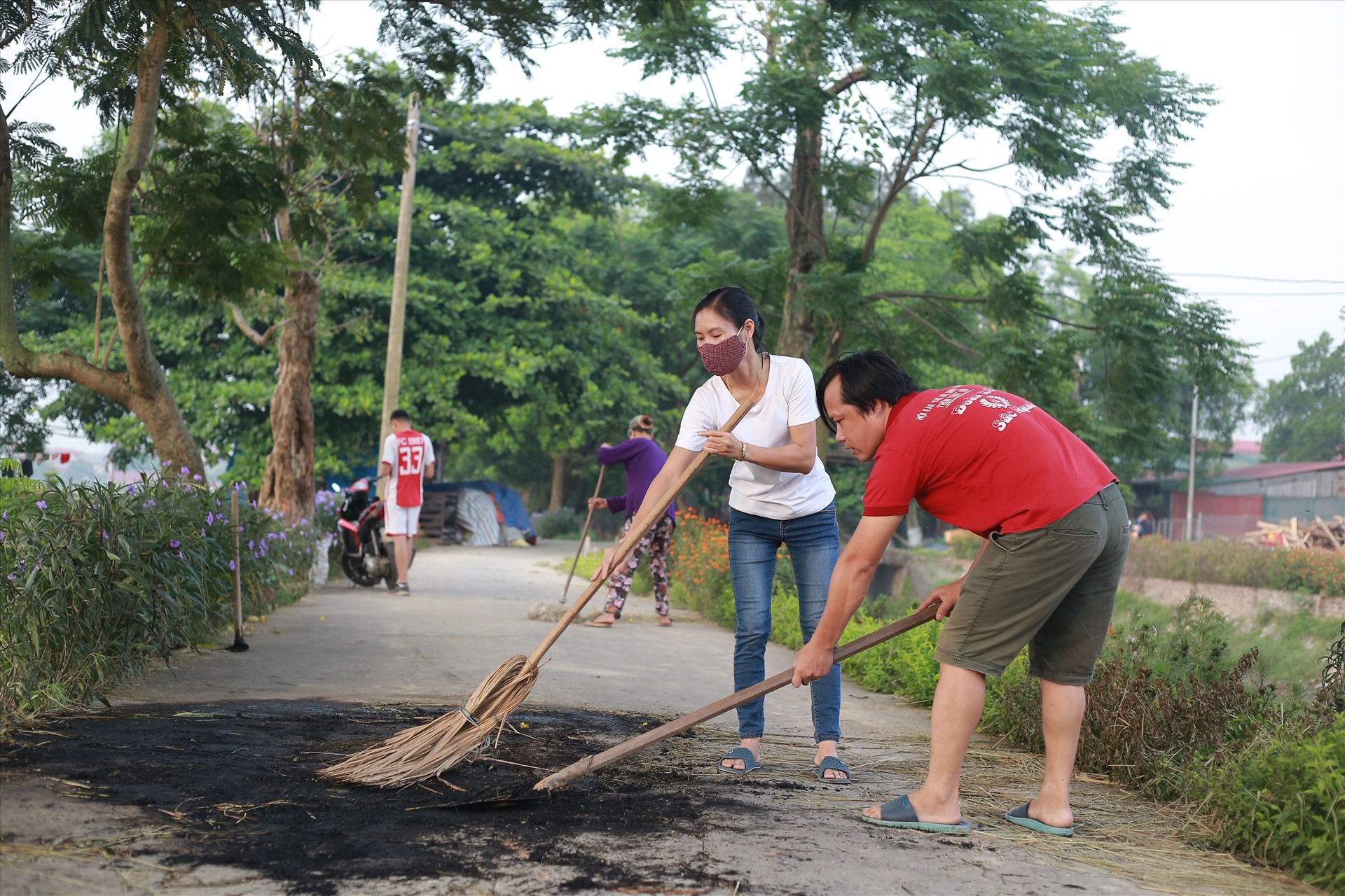 Anh Nguyễn Vũ đang cùng mọi người quét dọn trên đường hoa Thụy Lôi. Ảnh: Thanh Nga