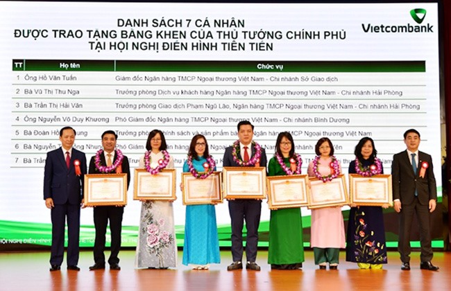 Ông Đào Minh Tú - Phó Thống đốc Thường trực NHNN (ngoài cùng bên trái) và ông Nghiêm Xuân Thành - Chủ tịch HĐQT Vietcombank (ngoài cùng bên phải) trao tặng Bằng khen của Thủ tướng Chính phủ và tặng hoa cho 7 tập thể và cá nhân thuộc Vietcombank. Ảnh: VCB