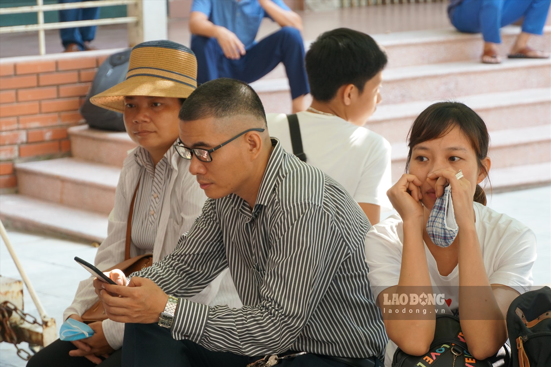 Nhiều phụ huynh tranh thủ vào chỗ bóng râm chờ con. Ảnh: Nhật Huy.