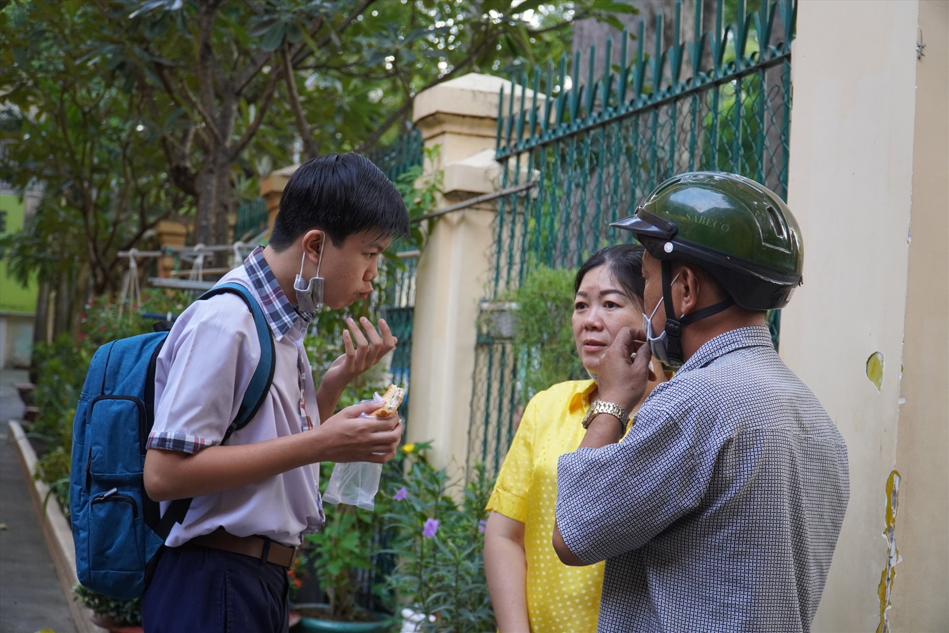 Một thí sinh vừa tranh thủ ăn sáng, vừa nói chuyện với bố mẹ.