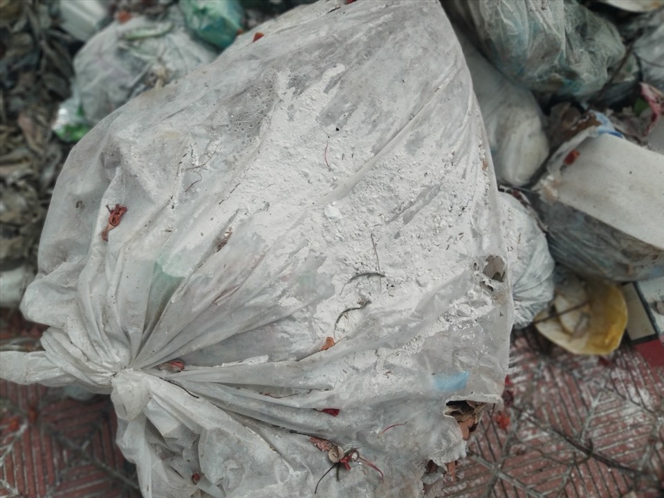 Rác được rắc vôi bột, phủ bạt nhưng vẫn không ngăn nổi mùi hôi thối bốc ra nồng nặc. Ảnh: Lan Nhi