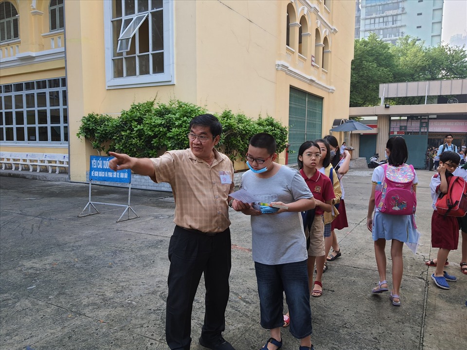 Cán bộ coi thi hướng dẫn các thí sinh vào phòng thi. Một số em nhầm địa điểm thi kịp thời được hỗ trợ tới đúng trường thi. Ảnh: Huyên Nguyễn
