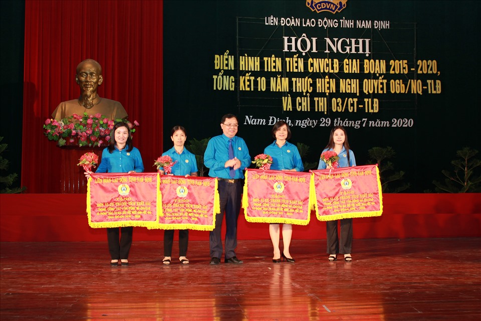 Đồng chí Vũ Văn Nghĩa – Chủ tịch LĐLĐ tỉnh Nam Định – trao cờ tới các tập thể vì có thành tích xuất sắc trong vận động nữ công nhân viên chức lao động và phong trào thi đua “Giỏi việc nước, đảm việc nhà” giai đoạn 2010-2020. Ảnh: Quế Hương