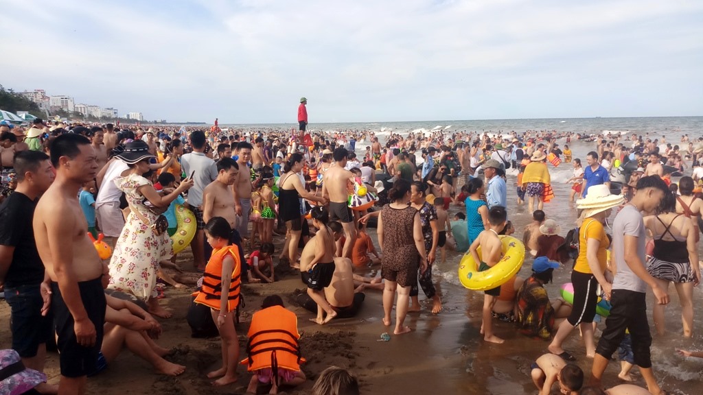 Bãi biển chật kín, du khách chen chân tắm biển. Ảnh: Quách Du