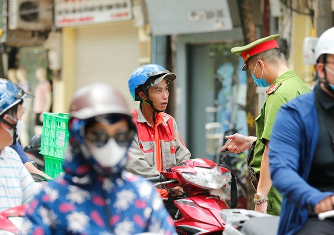 Những người tham gia giao thông dừng đèn đỏ tại ngã tư cũng được nhắc nhở đeo khẩu trang. Ảnh: Như Ý