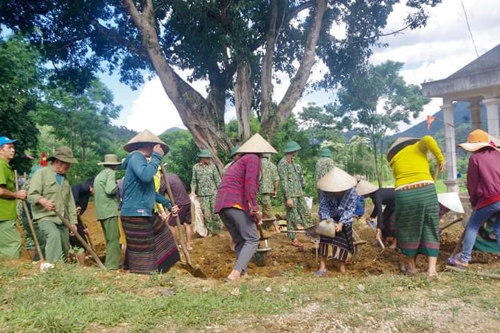 Cán bộ, chiến sĩ giúp dân san lấp mặt bằng sân văn hóa của bản. Ảnh: Tâm Quang
