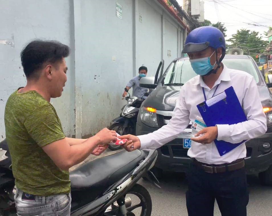 Cán bộ phường phát khẩu trang cho người vi phạm. Ảnh: Hữu Huy