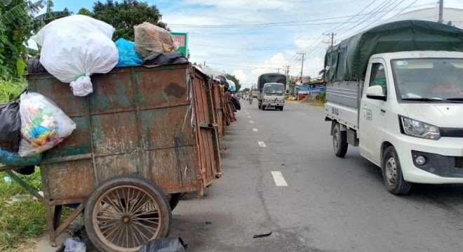 Các xe rác đậu tràn ra lòng đường trên quốc lộ 91B, gây mất an toàn giao thông. Ảnh: P.V.
