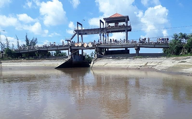 Người dân sốt ruột đứng trên cống đập Ba Lai theo dõi việc tìm kiếm các nạn nhân vụ chìm ghe. Ảnh: Thanh Huyền
