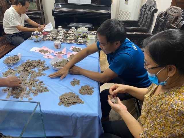 Cán bộ Bảo tàng Hà Tĩnh nghiên cứu, phân loại niên đại của các đồng tiền mà người dân đào được. Ảnh: BT.
