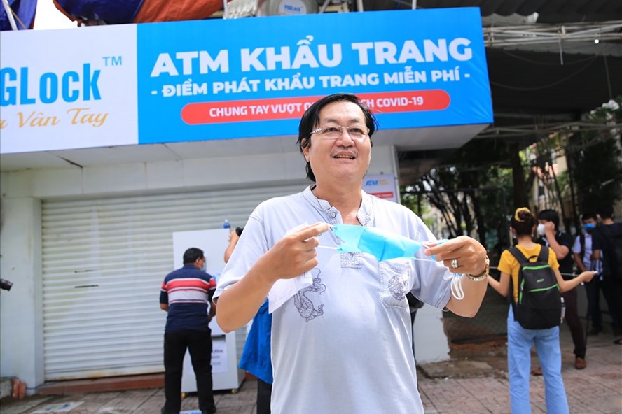 Người dân tiếp nhận khẩu trang từ điểm “ATM khẩu trang miễn phí” của anh Hoàng Tuấn Anh. Ảnh: Phạm Đông - Hữu Huy