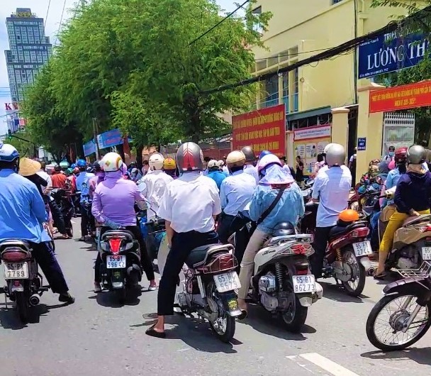 Phụ huynh rước con bằng xe gắn máy đậu dưới lòng đường gây ra cảnh ùn tắc và cản trở giao thông. Ảnh: Thành Nhân