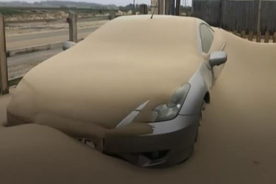 Một chiếc xe ô tô bị ngập trong đống cát lớn sau khi bão cát tấn công. Ảnh: Daily Mail