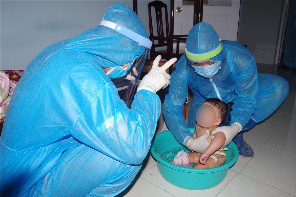 Nhân viên khu cách ly tắm cho các cháu