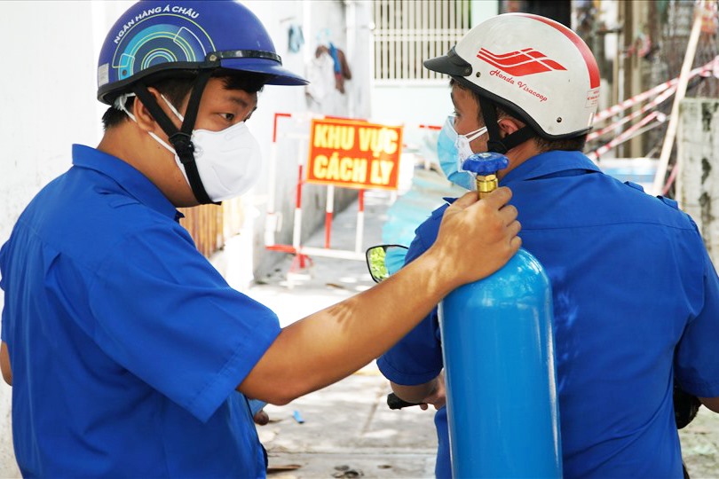 Những “shipper” áo xanh tình nguyện đến tận nhà giao bình ôxy cho các F0. Ảnh: Khánh Linh